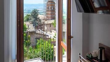 Una stanza con balcone, una scrivania e vista su un edificio in fase di ristrutturazione.