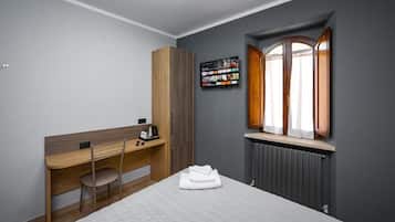 A hotel room with a bed, a desk, a chair, a television, and a window with curtains.