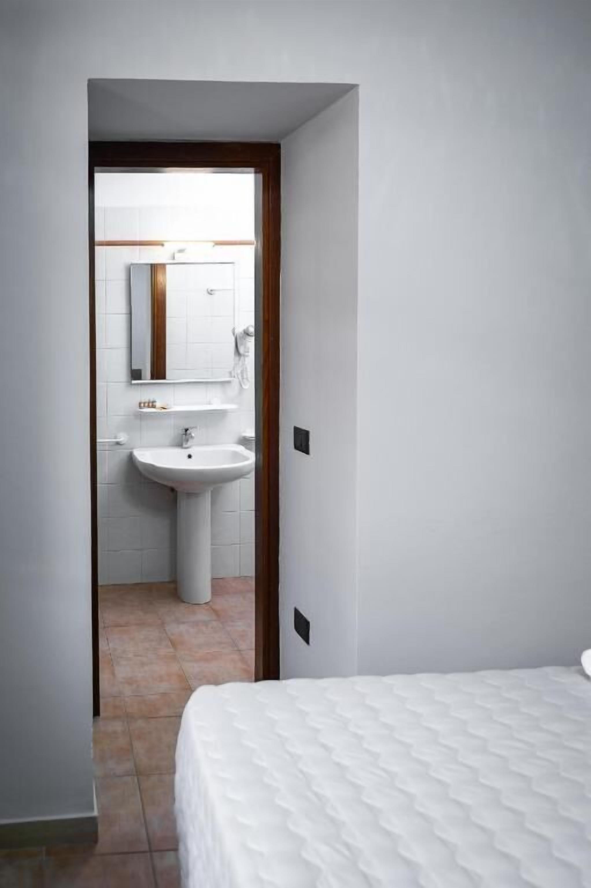Ein schmaler Flur, der zu einem Badezimmer mit Waschbecken und Spiegel führt.