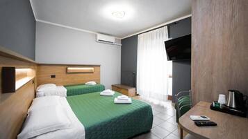 Habitación de hotel con dos camas, un escritorio, un televisor y aire acondicionado.