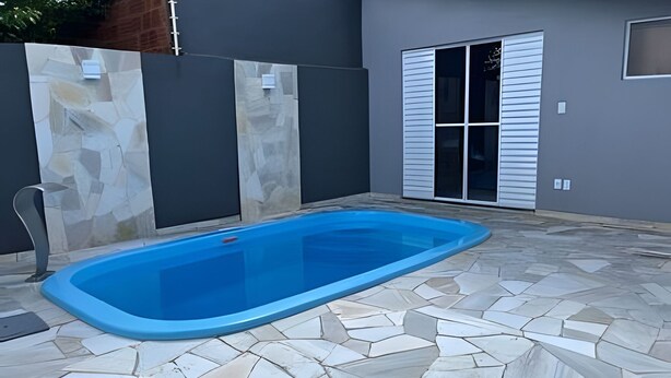 A swimming pool with a tiled deck, a metal fence, and a sliding glass door. - Casa do Bruno (Zangirolami)