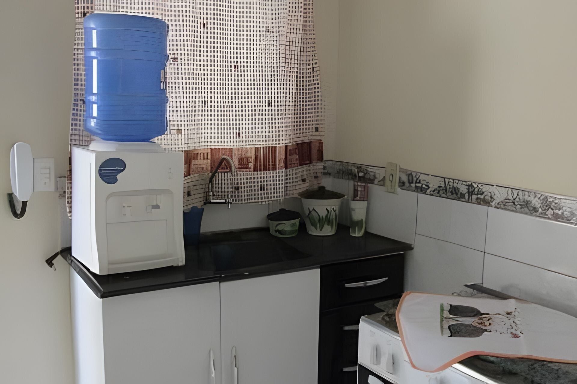 Une cuisine équipée d’un distributeur d’eau, d’une machine à café et d’un four à micro-ondes, le tout placé sur le plan de travail.