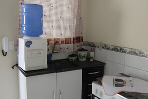A kitchen with a water dispenser, a coffee maker, and a microwave on the counter. - Casa do Bruno (Zangirolami)