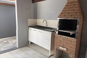 A compact kitchen with a built-in grill and a small sink. - Casa do Bruno (Zangirolami)