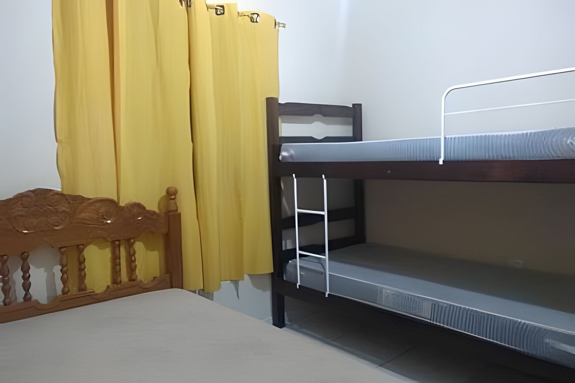 Ein Stockbett mit einem Holz-Kopfteil, einer weißen Leiter und einem gelben Vorhang.