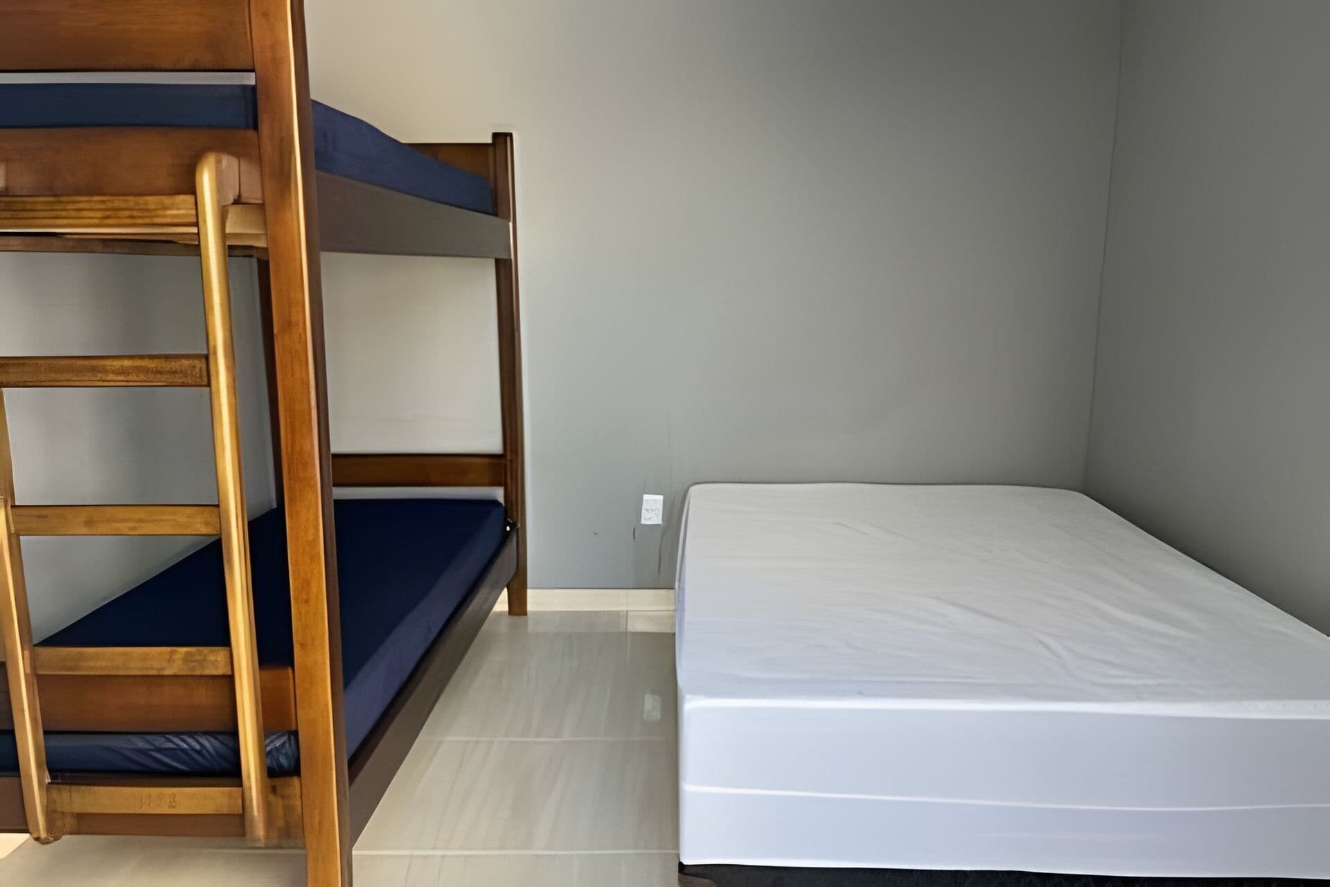A bunk bed with a mattress and a single bed with a mattress.
