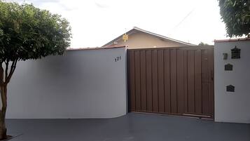 Una entrada con portón, un árbol y un edificio de techo plano.