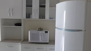 A kitchen with white cabinets, a microwave, and a refrigerator.
