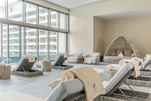 A modern spa area with loungers, a hanging chair, and a view of a high-rise building. - Cozy 1-bedroom condo in beautiful Cancun with fitness room and AC (cancun)