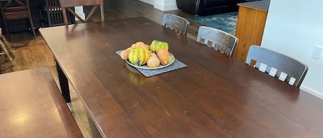 Une salle à manger avec une table en bois, des chaises et un panier de fruits.