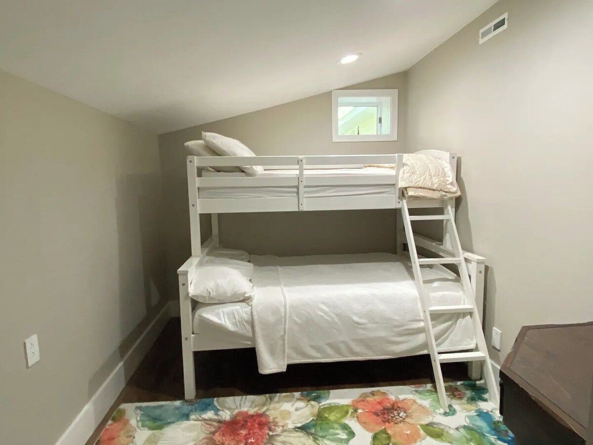 A bunk bed with a ladder, a small window, and a floral-patterned rug.