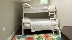 Una cama litera con escalera, una ventana pequeña y una alfombra estampada con motivos florales.