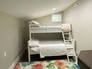 Ein Stockbett mit einer Leiter, einem kleinen Fenster und einem Teppich mit Blumenmuster.