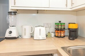 Eine Küchenarbeitsplatte mit einem Mixer, einem Wasserkocher, einem Toaster, einer Kaffeemaschine und einem Gewürzregal.