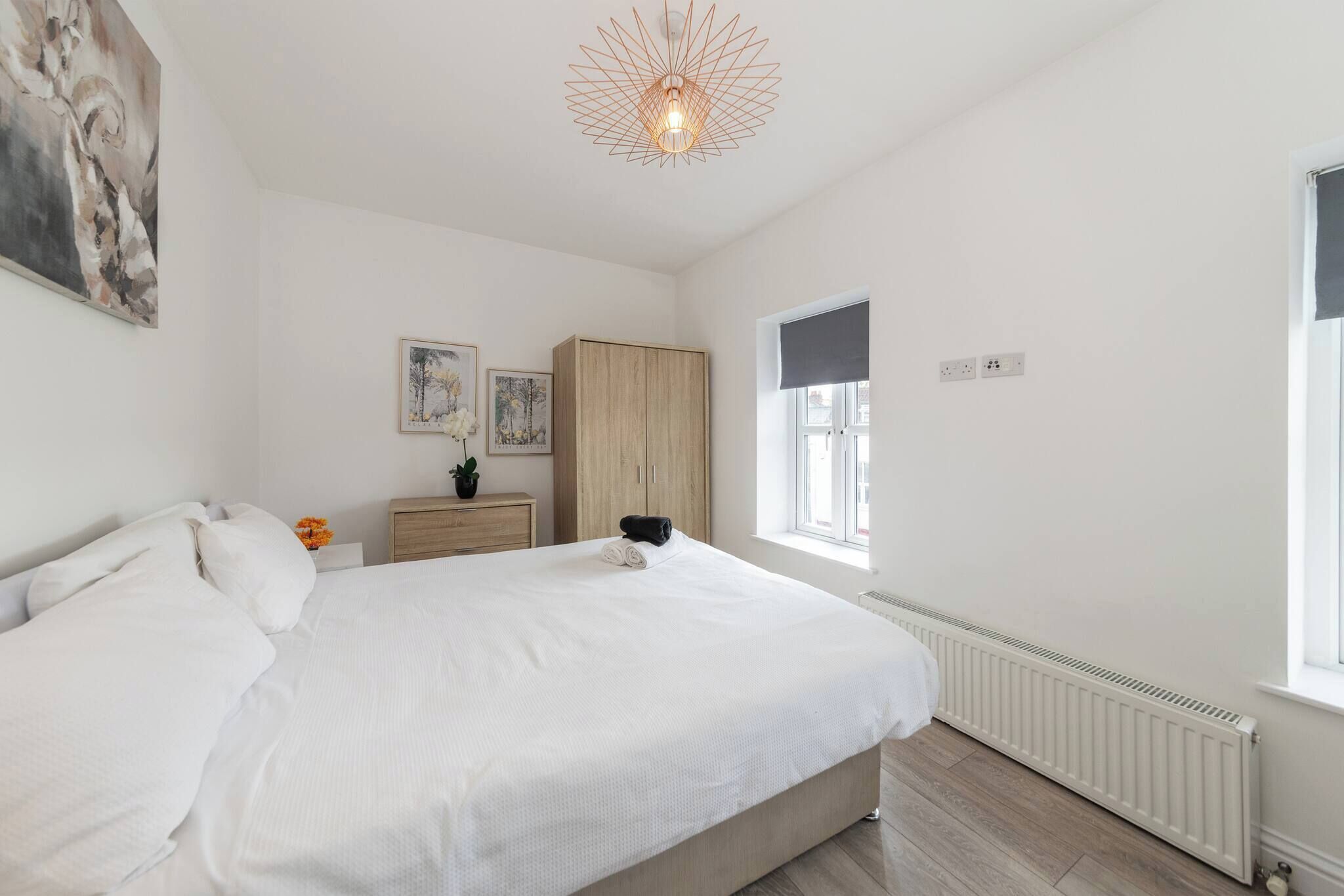 A bedroom with a large bed, a wardrobe, a nightstand, and a radiator.