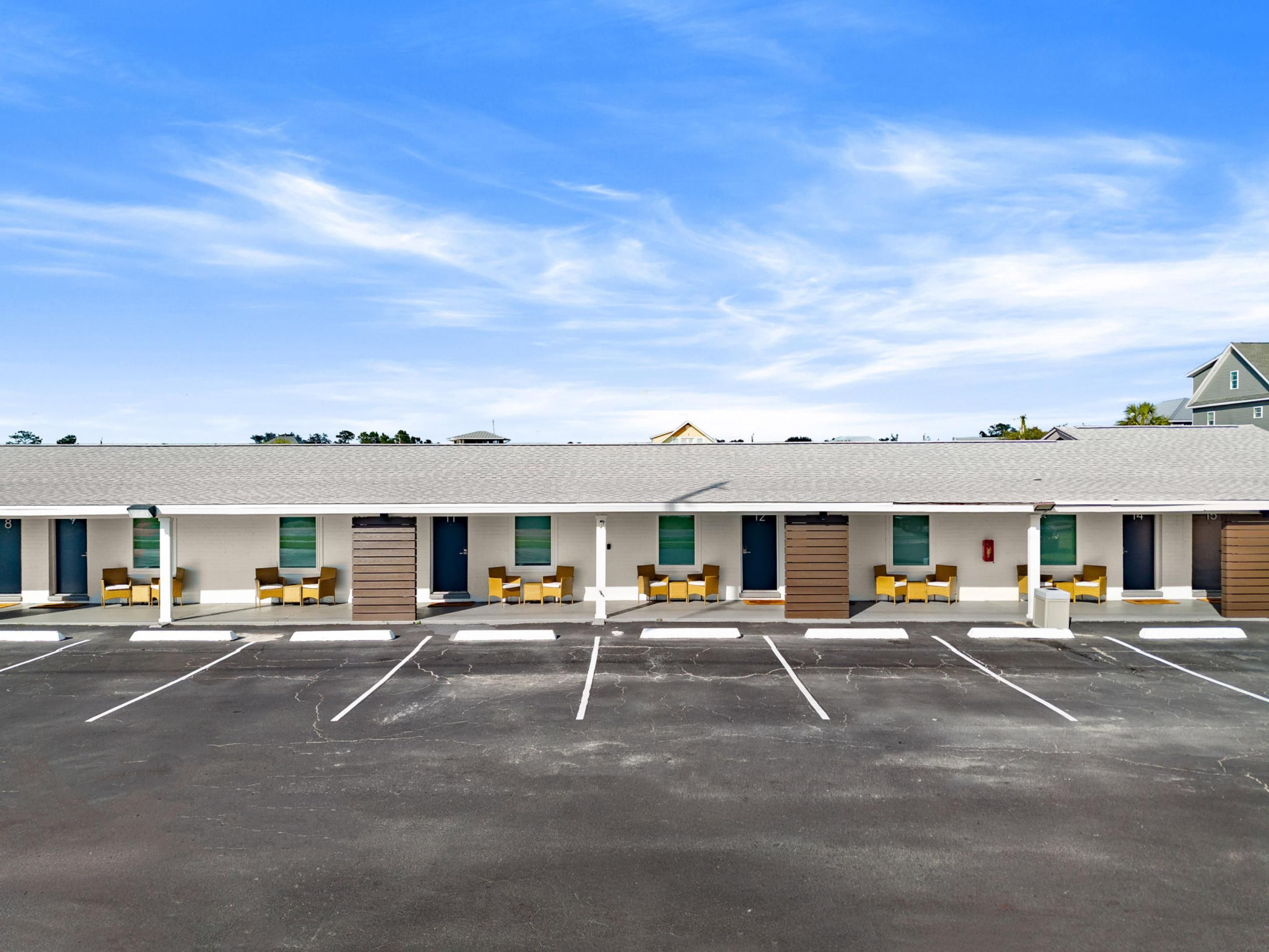 Il s'agit d'un motel doté de nombreuses chambres, chacune ayant une porte et une fenêtre. Un parking se trouve devant le motel.