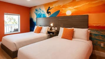Habitación de hotel con dos camas, una mesita de noche, un mural en la pared y una ventana con vistas.