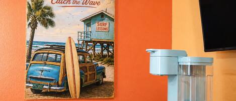 Une affiche ancienne représentant Port St. Joe, avec des cours de surf, une voiture bleue et un filtre à eau bleu posé sur une table.
