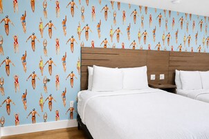 Ein Hotelzimmer mit einem großen Bett, einem hölzernen Kopfteil und einer Wand mit einem Muster von schwimmenden Personen.