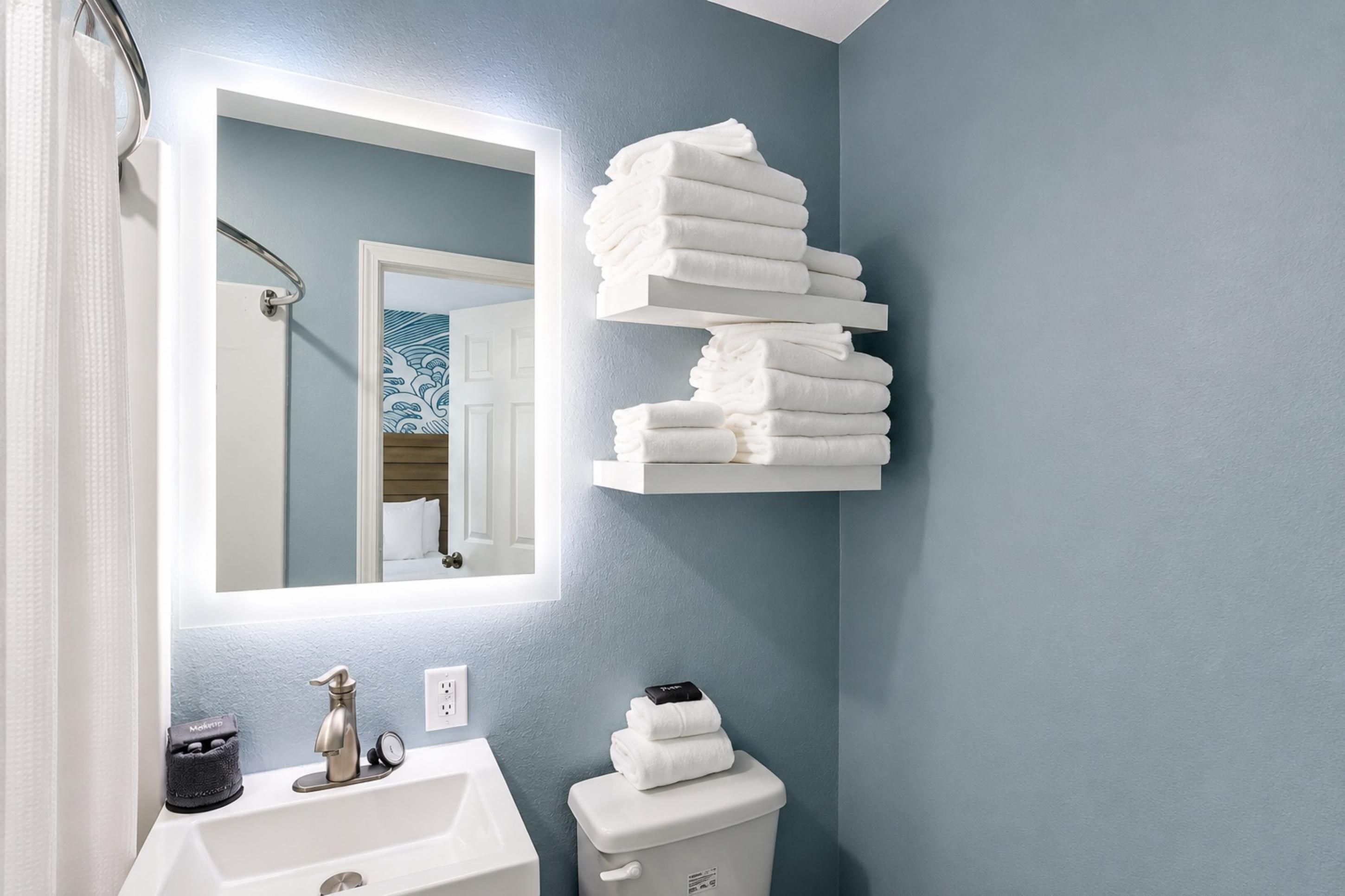 Un baño con lavamanos, inodoro y toallero con toallas dobladas.