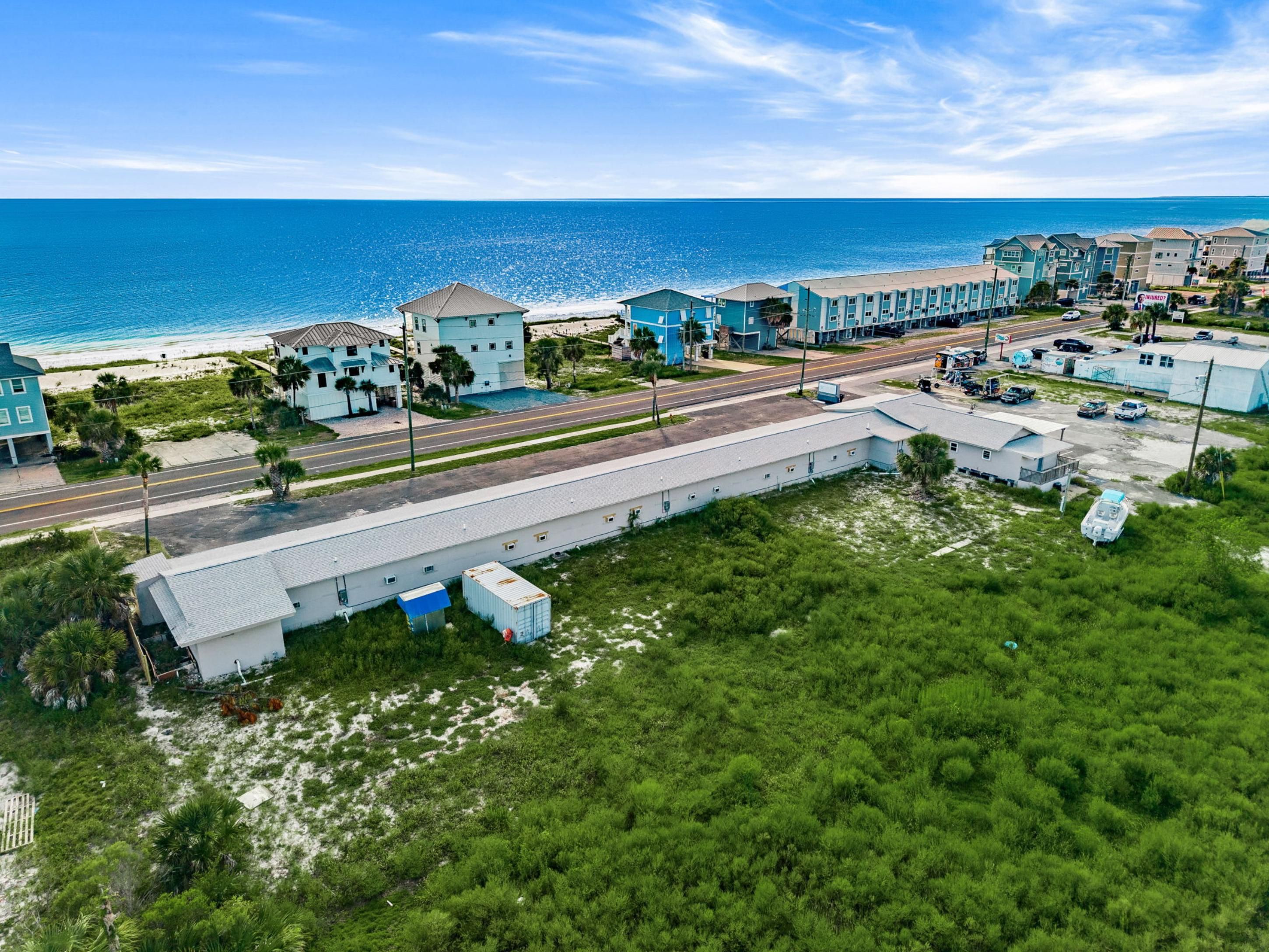 A coastal hotel with multiple buildings, a road, and a beach.