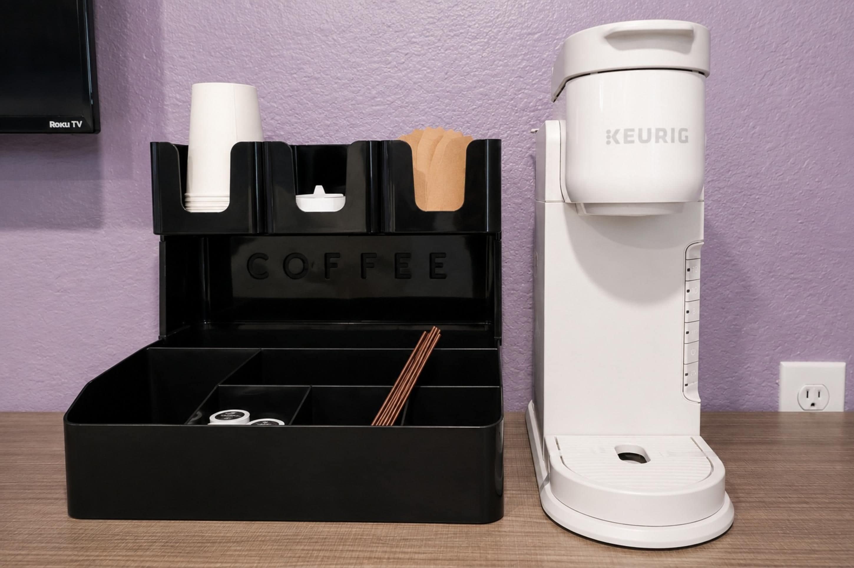 Uma cafeteira e um suporte para cápsulas de café com um letreiro escrito 'COFFEE' sobre uma mesa.