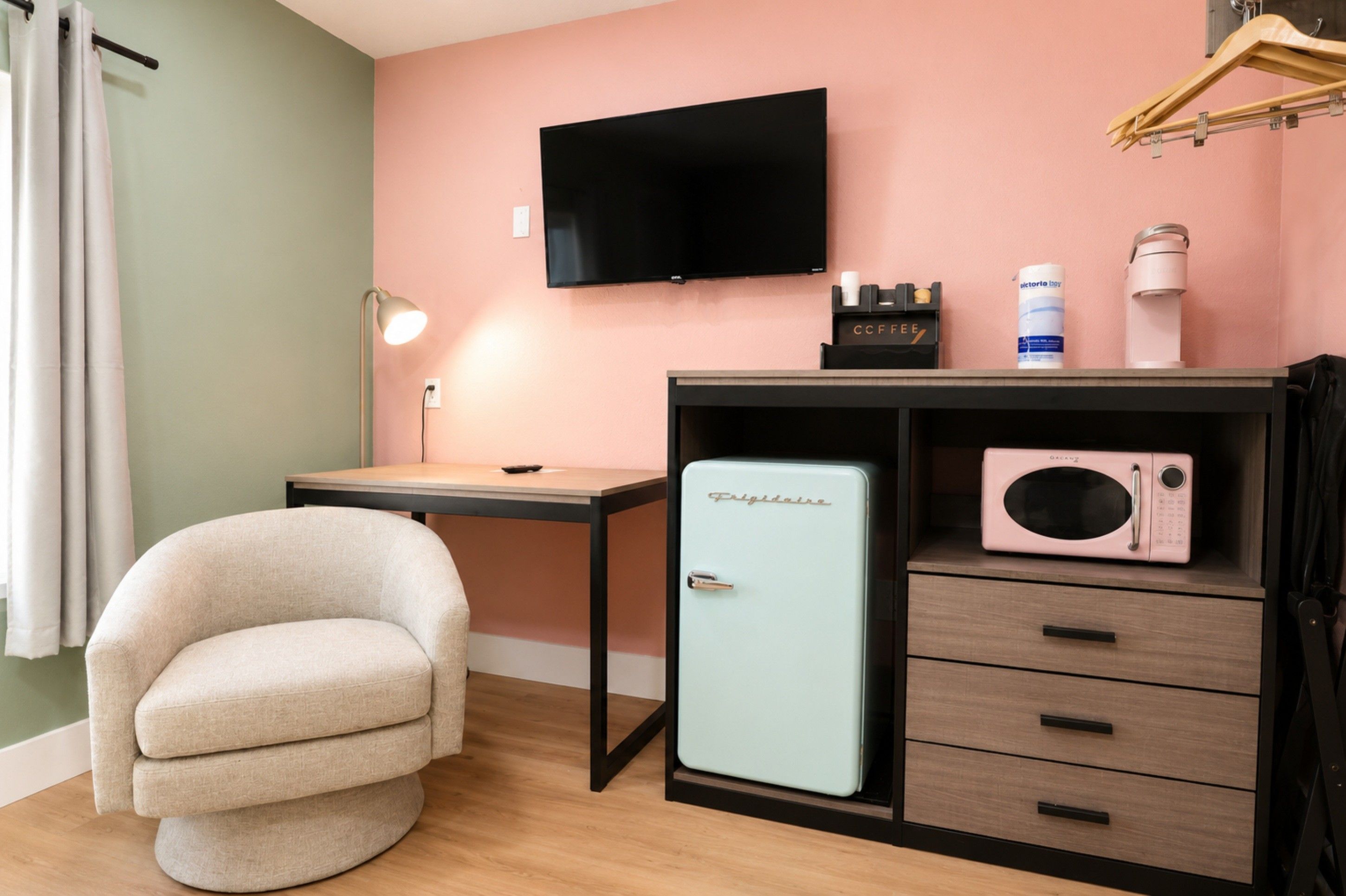 A compact room with a bed, a desk, a chair, a television, a microwave, and a small refrigerator.