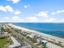 Zona residencial costera con playa, casas y una carretera.