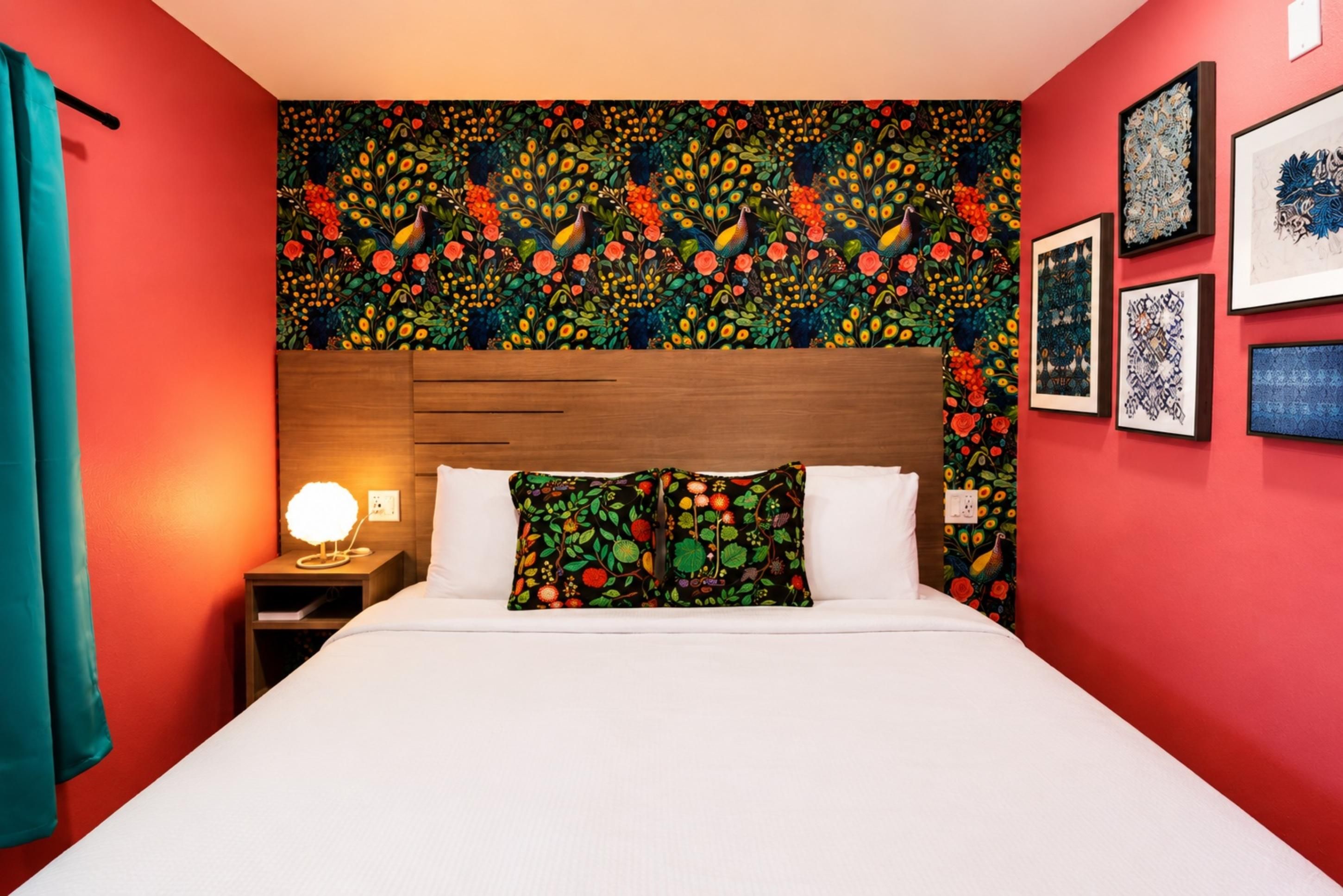 Habitación de hotel con papel tapiz floral llamativo, cabecera de madera, cama blanca y mesita de noche con lámpara.
