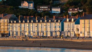A row of terraced houses along a beach with people walking on the promenade.