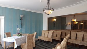 A dining area with a checkered floor, a table with a white tablecloth, wicker chairs, and a chandelier.