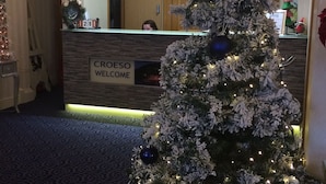 A reception area with a Christmas tree, a chandelier, and a 'CROESO WELCOME' sign.