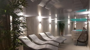 A spa area with three lounge chairs, a plant, and a water feature.
