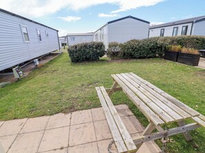 A grassy area with a picnic table and portable mobile homes in the background. - The Retreat (Holywell)