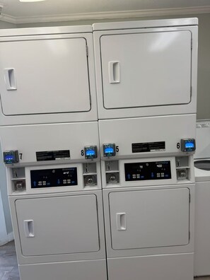 Una pila de cuatro lavadoras blancas con pantallas digitales y paneles de control.