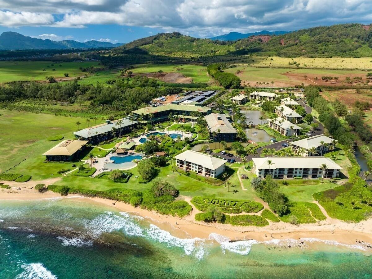 Un resort con varias edificaciones, una playa y un campo de golf.
