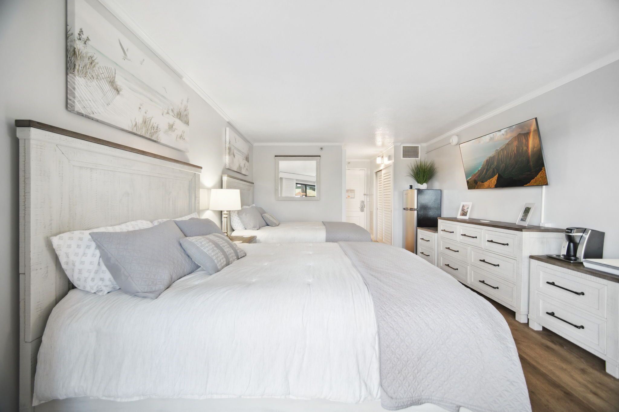 A bedroom with a large bed, bedside tables, a dresser, and a painting on the wall.