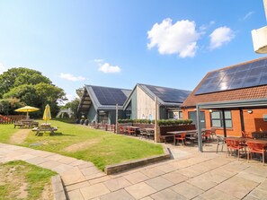 A patio area with outdoor seating and a building with solar panels. - Forest Retreat - Fo26 (Saxmundham)