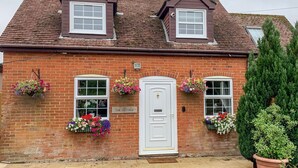 A brick cottage with a white door, two windows, and flower boxes. - The Cottage (Salisbury)