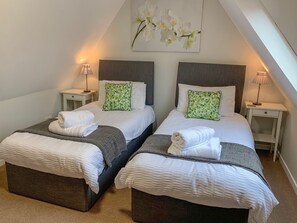 Ein Doppelzimmer mit zwei Betten, jeweils mit Nachttisch und Lampe.