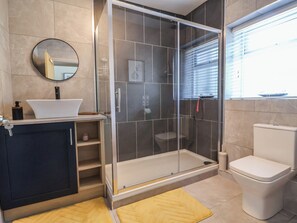 Ein modernes Badezimmer mit einer Duschkabine, einem weißen Waschbecken und einer Toilette.