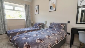 Une chambre avec deux lits, un bureau et une fenêtre avec des rideaux.