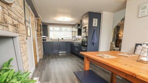 Une cuisine moderne avec des meubles de couleur grise, un banc en bois et un sol carrelé.
