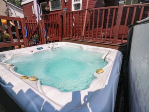 A hot tub with a white cover, surrounded by a wooden deck and a red fence. - The Cabin (Kirkcaldy)