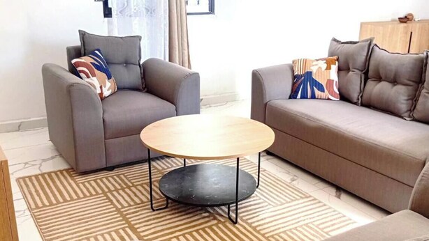 Una sala de estar con dos sofás, una mesa de centro redonda y alfombras estampadas.