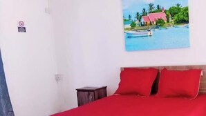 Una cama con ropa de cama roja, un cabecero de madera y dos mesitas de noche.
