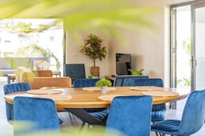 A dining area with a wooden table, blue upholstered chairs, and woven placemats. - Villa Mambo Royale - walking distance Mambo Beach (Willemstad)