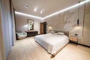 A modern bedroom with a large bed, a bedside table, a nightstand, a chair, a mirror, and a wardrobe. - Lux Villa In The Heart of Yerevan Verin Antarayin (Yerevan)