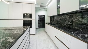 Eine moderne Küche mit weißen Schränken, einer schwarzen Marmorarbeitsplatte und einem eingebauten Backofen.