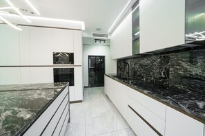 A modern kitchen with white cabinetry, a black marble countertop, and a built-in oven. - Lux Villa In The Heart of Yerevan Verin Antarayin (Yerevan)